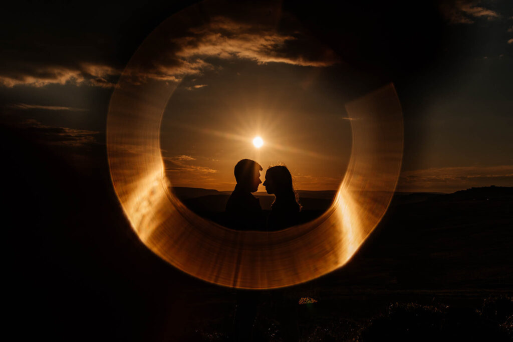 Flara z efektem pierścienia na zdjęciu dwojga narzeczonych wykonanym pod słońce.