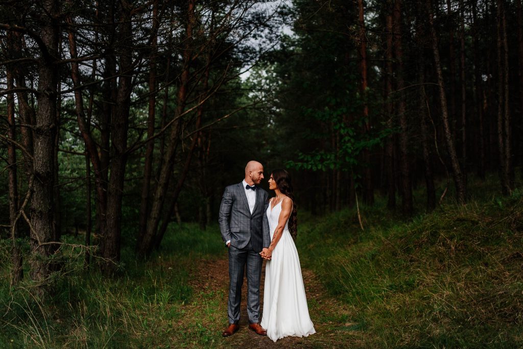 Para młoda pozująca do zdjęcia ślubnego w malowniczym lesie w Gdańsku.